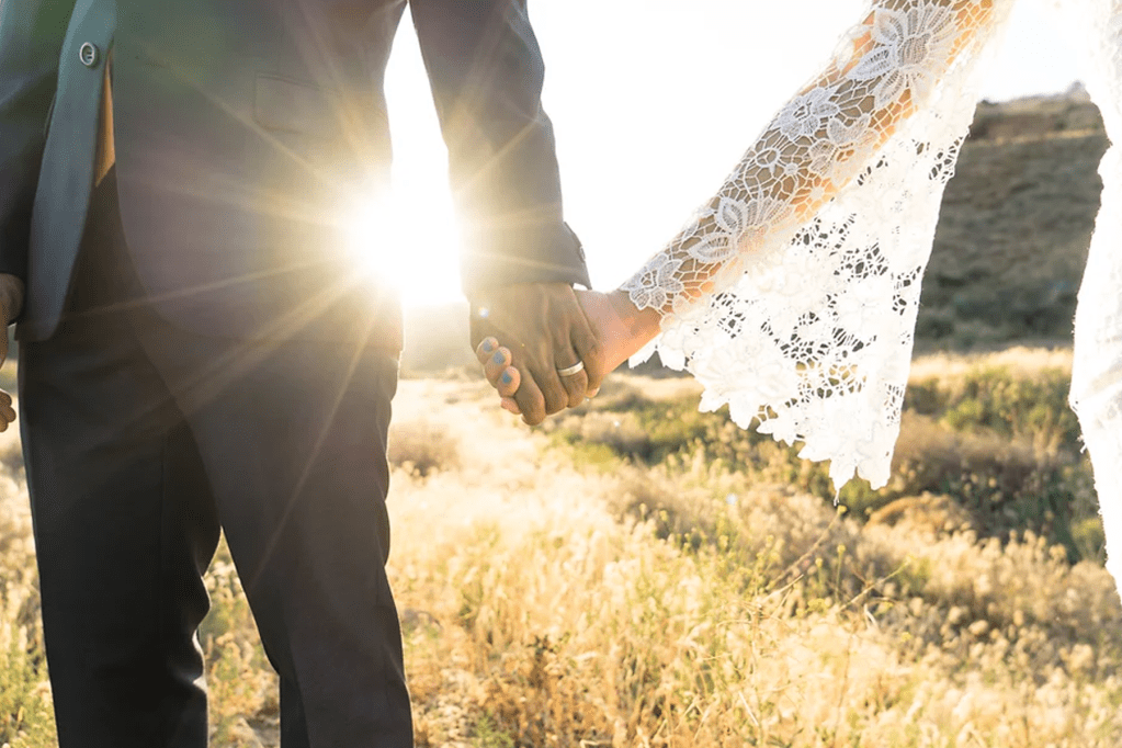 newlywed couple holding hands in the sunset